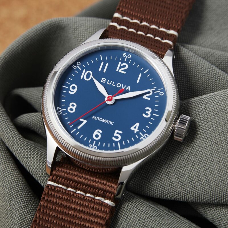 Bulova Orologio Automatico Da Uomo Modello 96A282, Ispirato Al Patrimonio Militare. Cassa In Acciaio Inox, Quadrante Blu Con Lancette Super-Luminova, Cinturino NATO In Nylon Marrone. Impermeabile 50m.